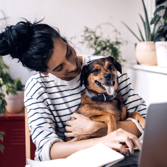 Foto de uma pessoa trabalhando de casa com cachorro no colo