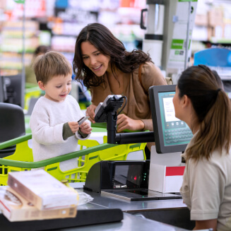 Imagem de uma mãe com o filho realizando o pagamento da compra