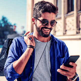 Foto de uma pessoa sorrindo com celular em uma mão e uma sacola de compras em outra